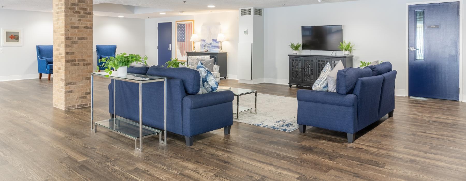 a lounge room with blue couches and a tv