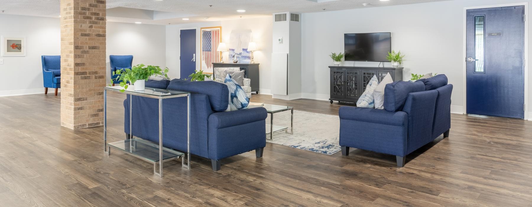 a lounge room with blue couches and a tv