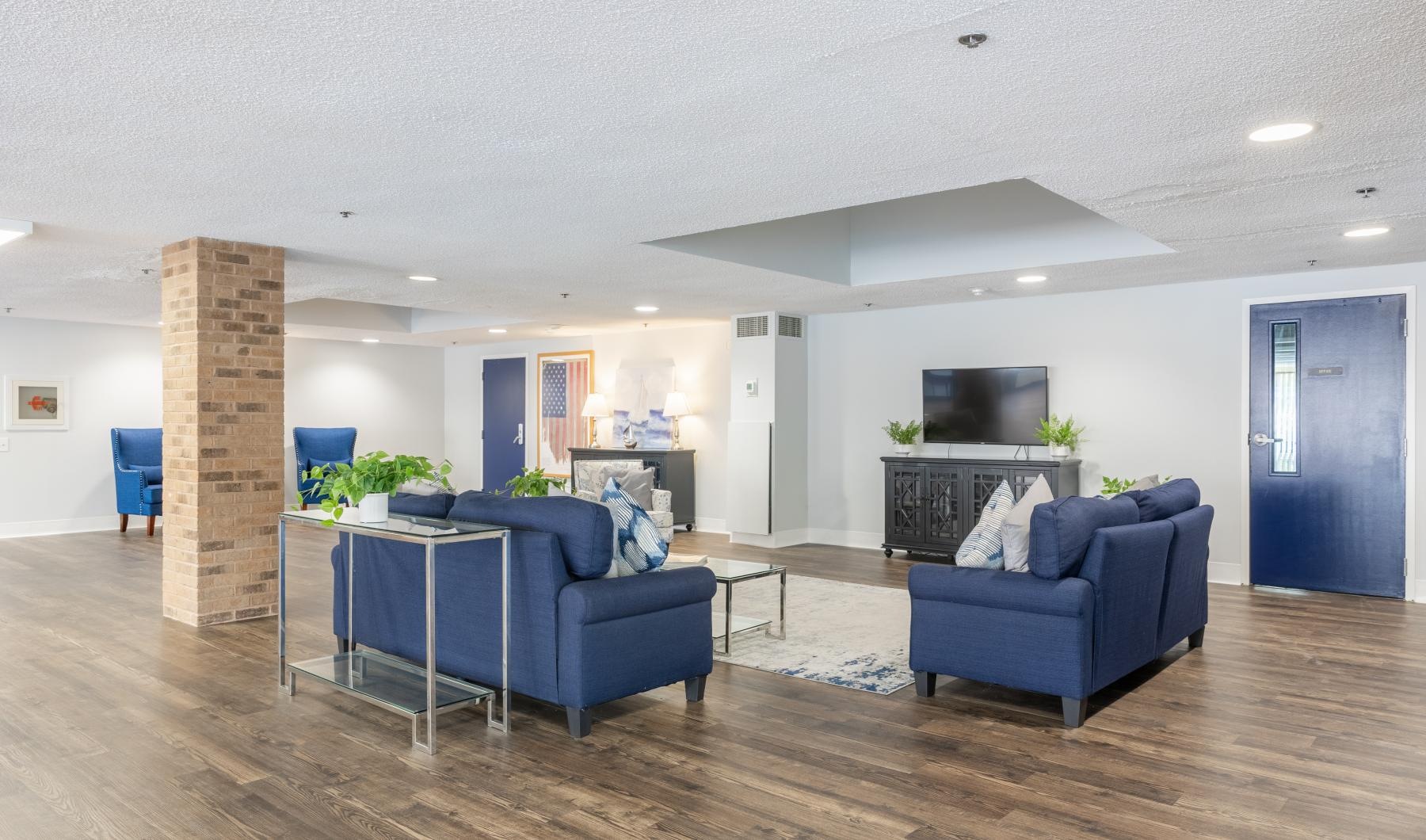 Settle into comfort at Serenity Towers at Brockton a lounge room with blue couches and a tv